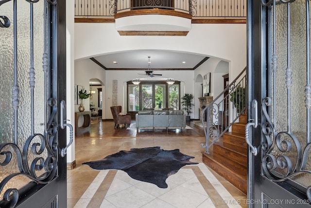 10626 S Joplin Ave, Tulsa, OK 74137 - tiled foyer with ceiling fan, arched walkways, ornamental molding, inlaid floor details, and a towering ceiling