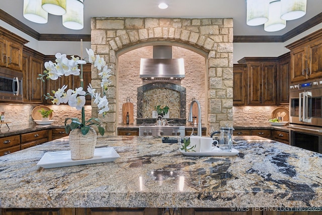 10626 S Joplin Ave, Tulsa, OK 74137 - kitchen with stainless steel appliances, light stone counters, decorative backsplash, crown molding, and wall chimney range hood
