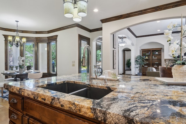 10626 S Joplin Ave, Tulsa, OK 74137 - kitchen featuring a chandelier, a sink, dark stone countertops, arched walkways, and crown molding