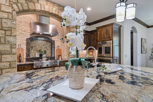 10626 S Joplin Ave, Tulsa, OK 74137 - kitchen featuring wall chimney range hood, stainless steel appliances, arched walkways, dark stone counters, and ornamental molding