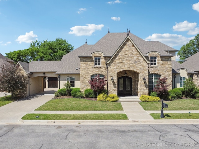 10626 S Joplin Ave, Tulsa, OK 74137 - french country style house featuring french doors, stone siding, a front yard, roof with shingles, and stucco siding