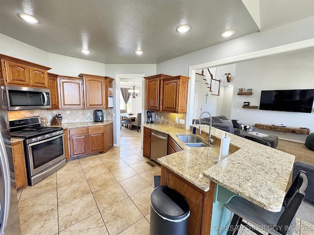 1412 Richmond Dr, Fort Gibson, OK 74434 - kitchen with a peninsula, a sink, open floor plan, a kitchen bar, and appliances with stainless steel finishes