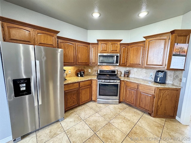 1412 Richmond Dr, Fort Gibson, OK 74434 - kitchen with light stone countertops, stainless steel appliances, brown cabinets, and tasteful backsplash