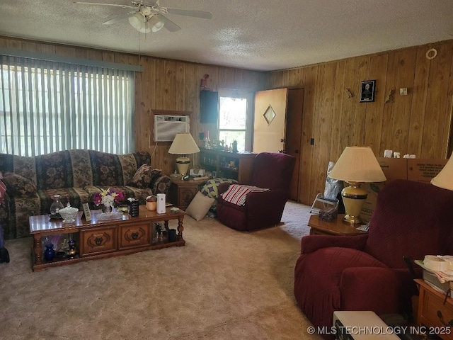 carpeted living area featuring wooden walls, a textured ceiling, a wall unit AC, and ceiling fan