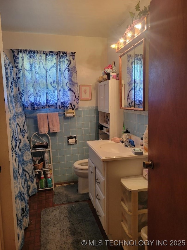 bathroom with a wainscoted wall, a shower with curtain, toilet, tile walls, and vanity