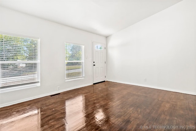 spare room with baseboards, wood finished floors, and visible vents