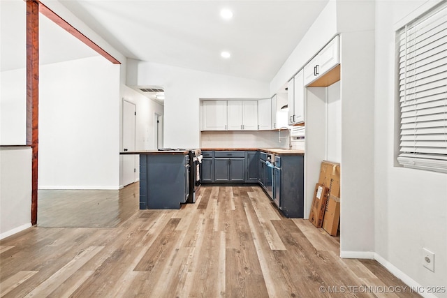 kitchen with white cabinets, lofted ceiling, light wood-type flooring, and blue cabinets