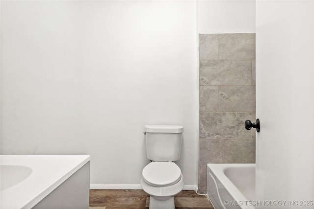 bathroom featuring baseboards, wood finished floors, vanity, and toilet