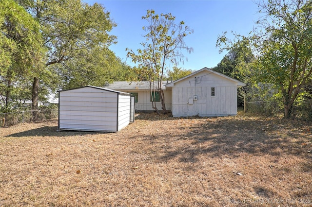 rear view of house with a storage shed, an outbuilding, and a fenced backyard