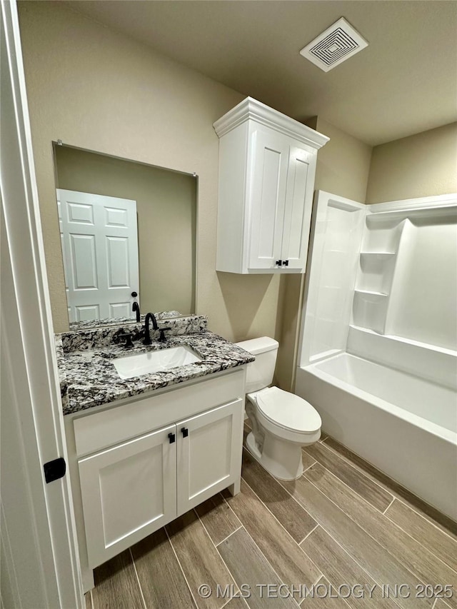 full bath with toilet, vanity, wood finish floors, visible vents, and bathing tub / shower combination