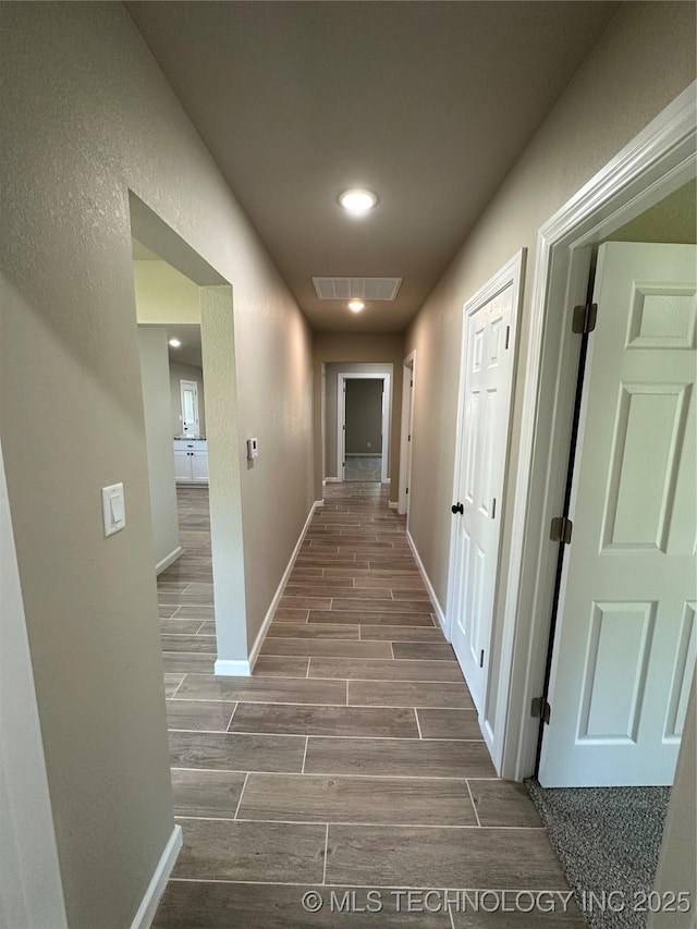 corridor with baseboards, visible vents, wood tiled floor, and recessed lighting