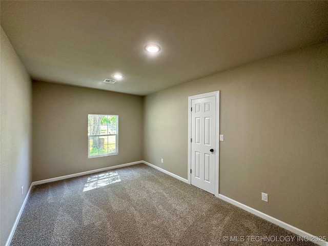 unfurnished room with carpet, visible vents, and baseboards