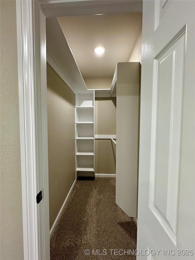 walk in closet featuring dark carpet