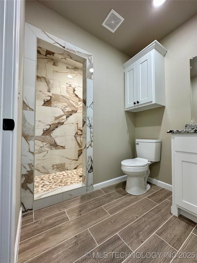full bath featuring wood tiled floor, visible vents, toilet, vanity, and a marble finish shower