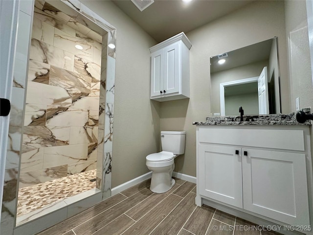 full bath featuring a marble finish shower, toilet, visible vents, vanity, and wood finish floors