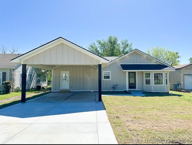 view of front facade featuring board and batten siding, a front yard, and concrete driveway