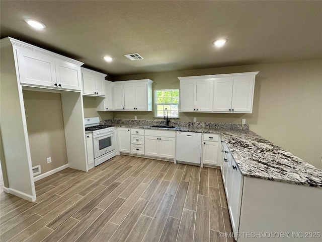 kitchen featuring visible vents, light wood finished floors, a sink, and white appliances