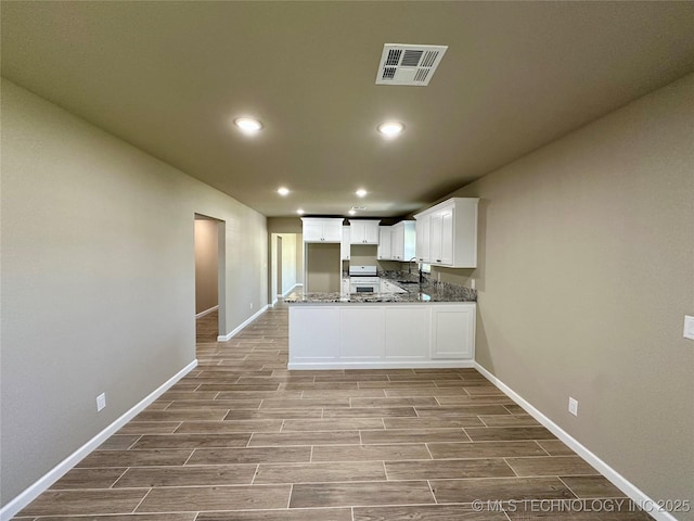 kitchen with baseboards, white cabinetry, wood finished floors, and visible vents