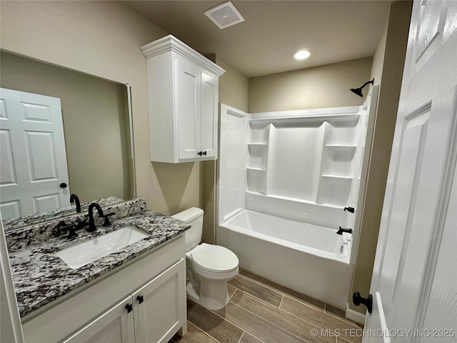 bathroom featuring wood tiled floor, visible vents, toilet, vanity, and tub / shower combination