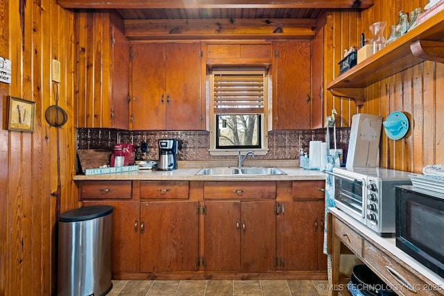 kitchen with wooden ceiling, a sink, and wooden walls