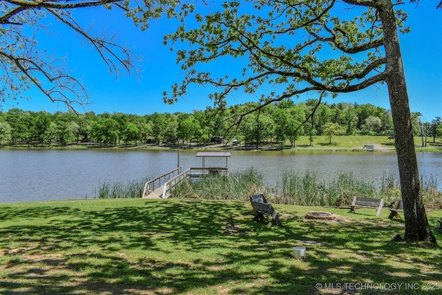 view of dock with an outdoor fire pit, a yard, a wooded view, and a water view