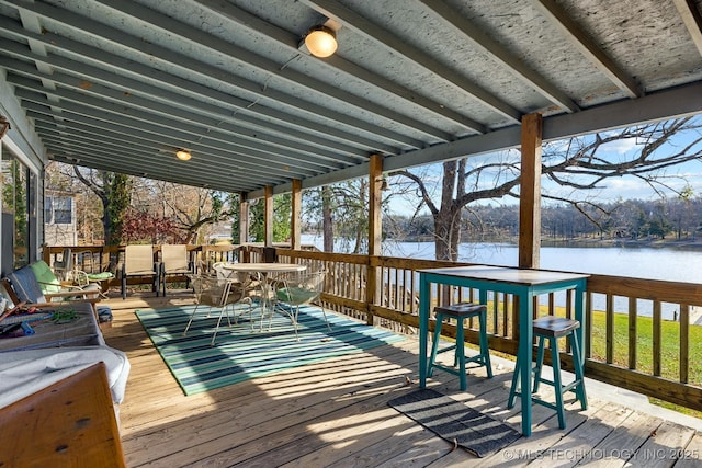 deck with outdoor dining space and a water view