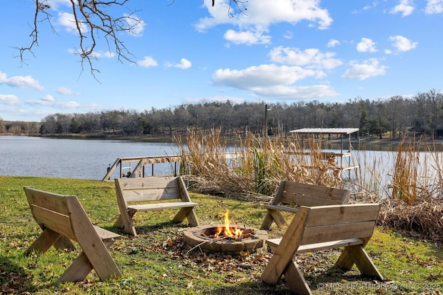dock area with a view of trees, a water view, and an outdoor fire pit