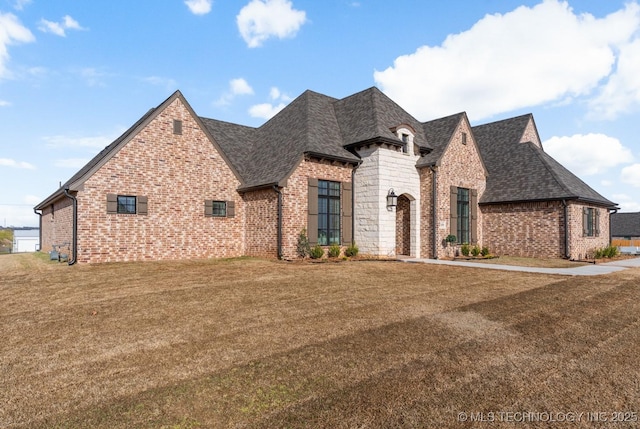 view of front of house with a front lawn, brick siding, and roof with shingles