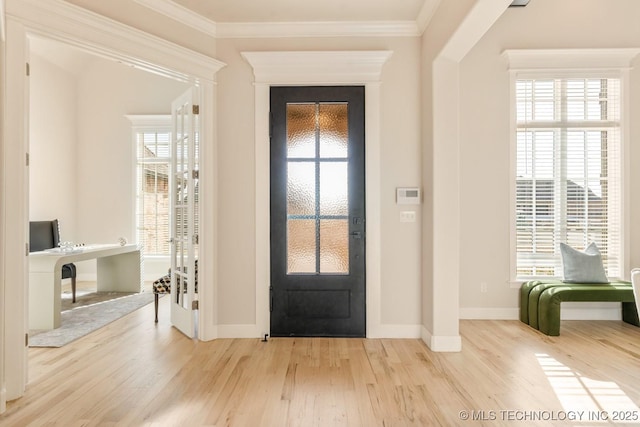 entryway featuring baseboards, wood finished floors, a wealth of natural light, and crown molding