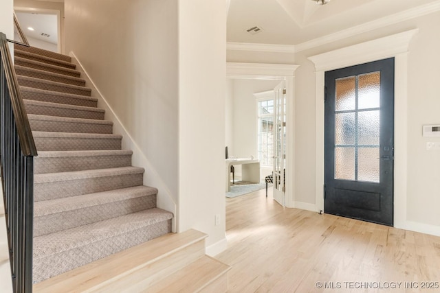foyer entrance with baseboards, wood finished floors, stairs, and ornamental molding