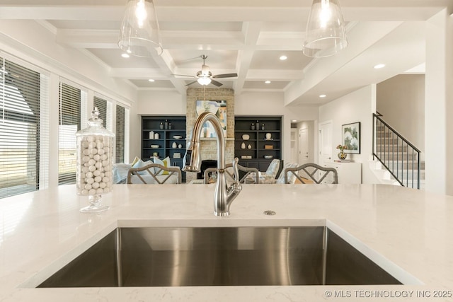kitchen with a sink, open floor plan, coffered ceiling, beamed ceiling, and a ceiling fan