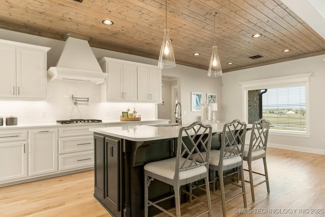 kitchen featuring light countertops, wooden ceiling, premium range hood, light wood-type flooring, and white cabinetry