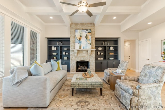 living room with beam ceiling, recessed lighting, coffered ceiling, a ceiling fan, and a stone fireplace