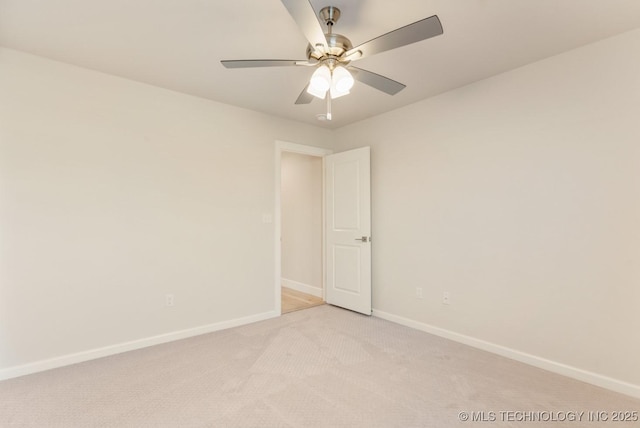 spare room featuring baseboards, a ceiling fan, and light carpet
