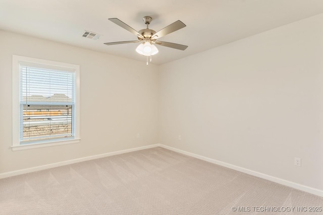 spare room with baseboards, visible vents, light colored carpet, and ceiling fan