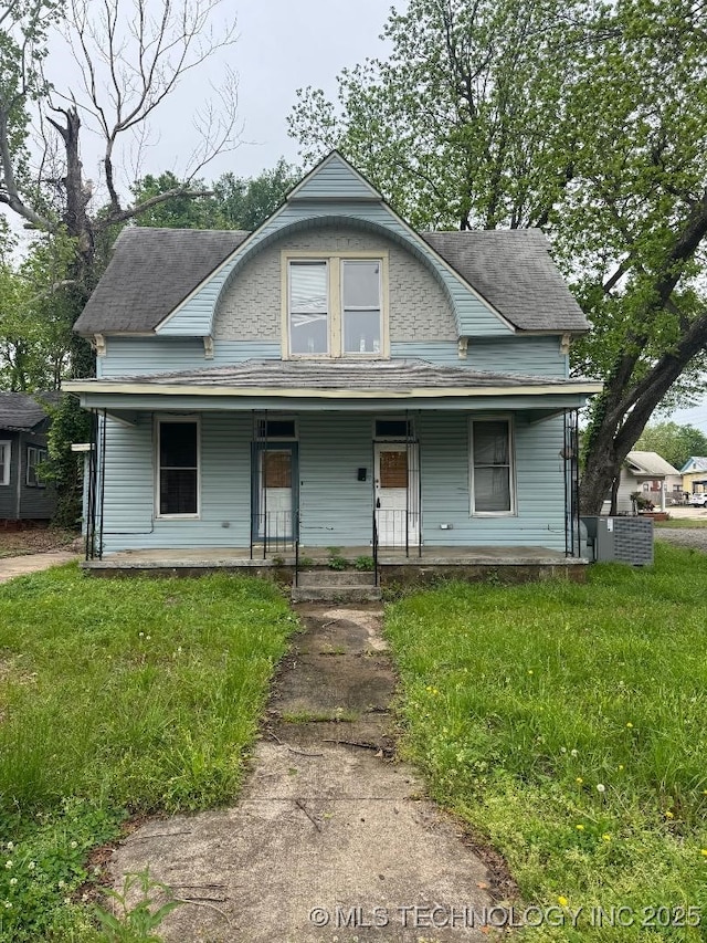 view of front of home featuring a shingled roof, a front yard, and covered porch