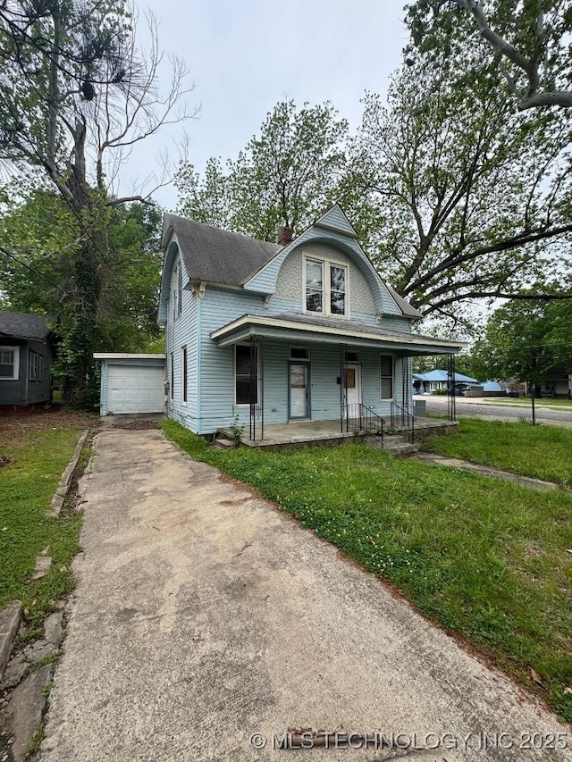 view of front of house featuring driveway, a front lawn, a chimney, and covered porch