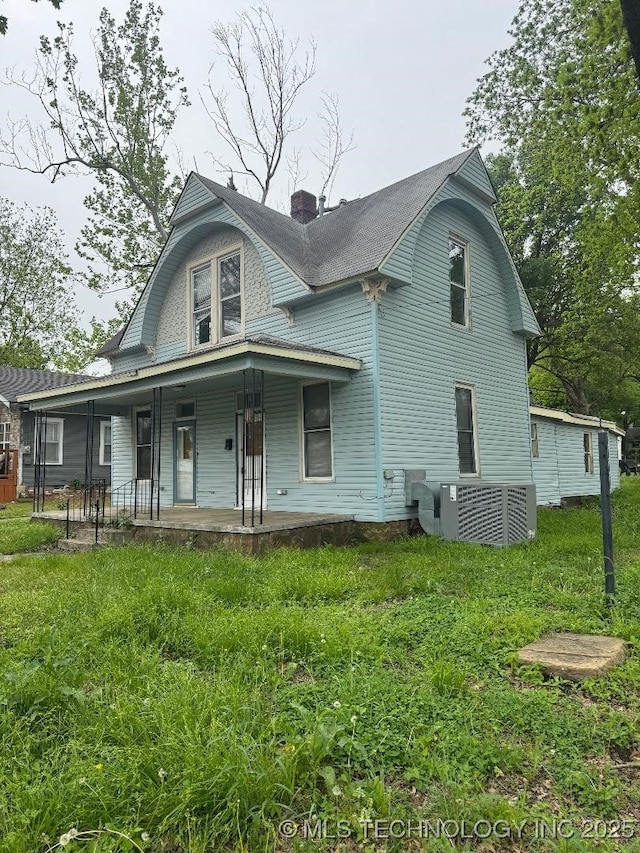 back of property featuring a porch, a lawn, and a chimney