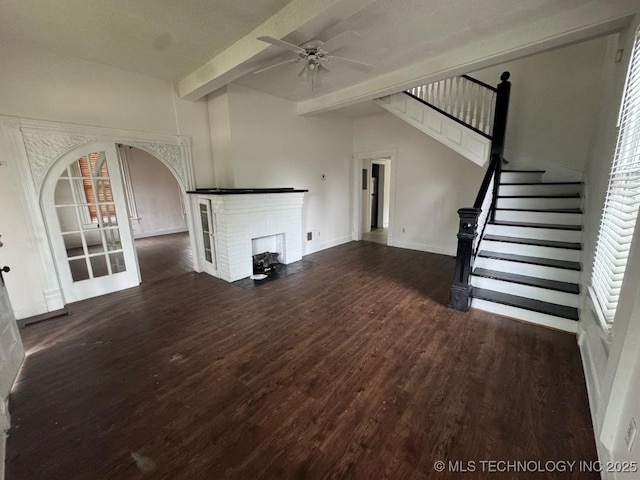 unfurnished living room with a fireplace, wood finished floors, a ceiling fan, and stairs