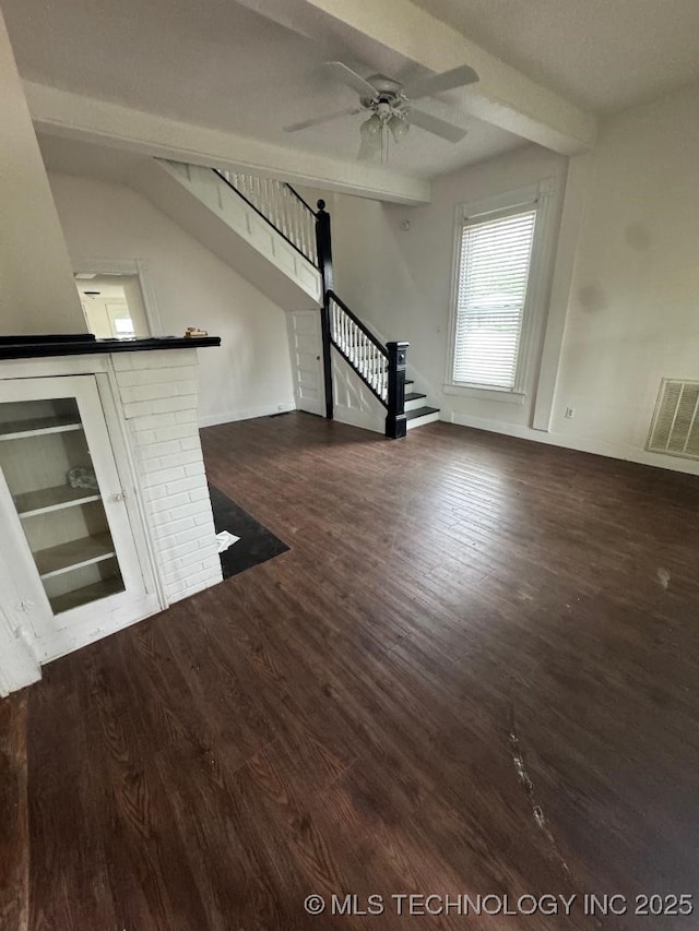 unfurnished living room with stairway, visible vents, dark wood-style flooring, baseboards, and ceiling fan