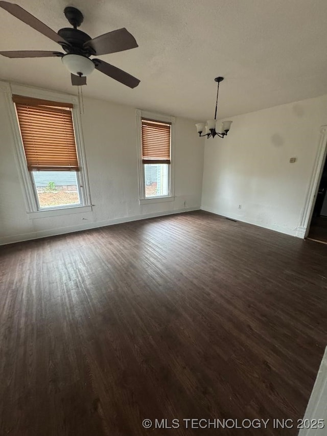 unfurnished room with baseboards, dark wood-style floors, and ceiling fan with notable chandelier
