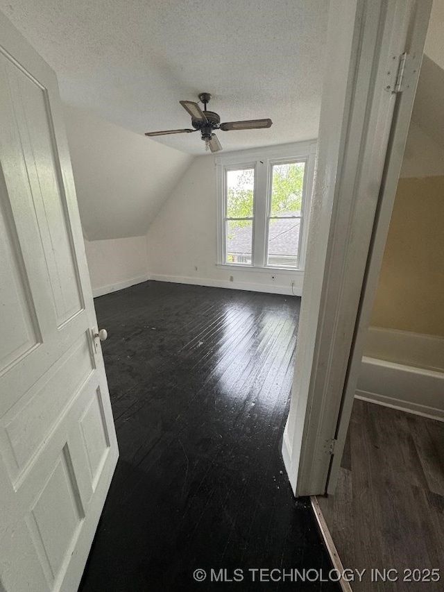 bonus room featuring ceiling fan, a textured ceiling, lofted ceiling, and dark wood-style flooring