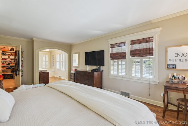 2412 E 23rd St, Tulsa, OK 74114 - bedroom with wood finished floors, a walk in closet, arched walkways, ornamental molding, and visible vents