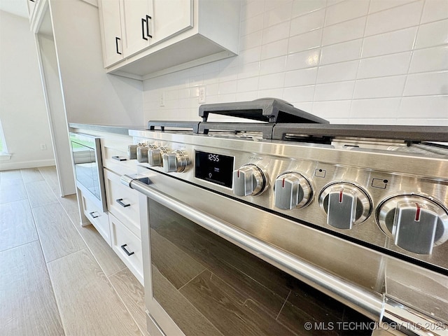 574 Woodlands Dr, Tahlequah, OK 74464 - kitchen view of stainless steel range with gas cooktop, backsplash, and white cabinetry
