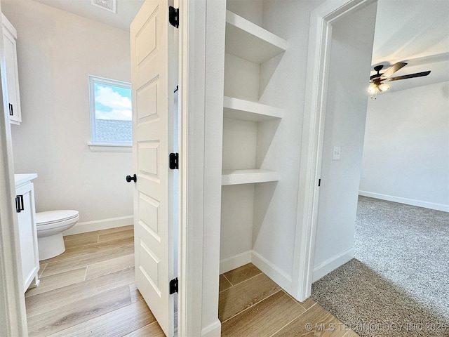 574 Woodlands Dr, Tahlequah, OK 74464 - bathroom with toilet, a ceiling fan, vanity, wood finished floors, and baseboards