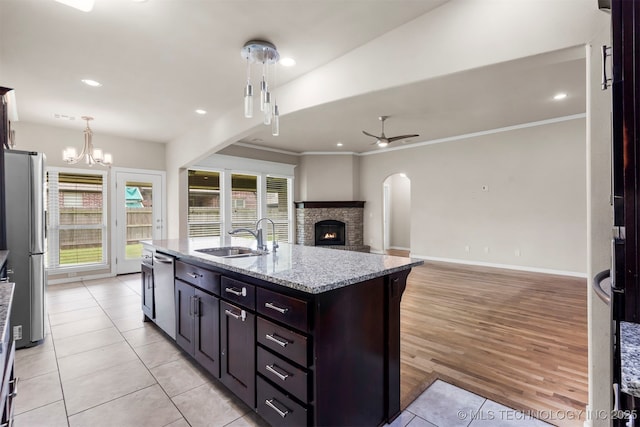 7056 E 124th St S, Bixby, OK 74008 - kitchen featuring stainless steel appliances, a sink, ceiling fan, light stone countertops, and an island with sink