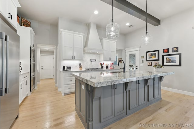 19340 E Canyon Ridge Rd, Owasso, OK 74055 - kitchen featuring a sink, white cabinets, premium range hood, backsplash, and appliances with stainless steel finishes