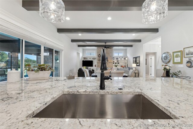 19340 E Canyon Ridge Rd, Owasso, OK 74055 - kitchen with a sink, ceiling fan with notable chandelier, open floor plan, light stone countertops, and beam ceiling