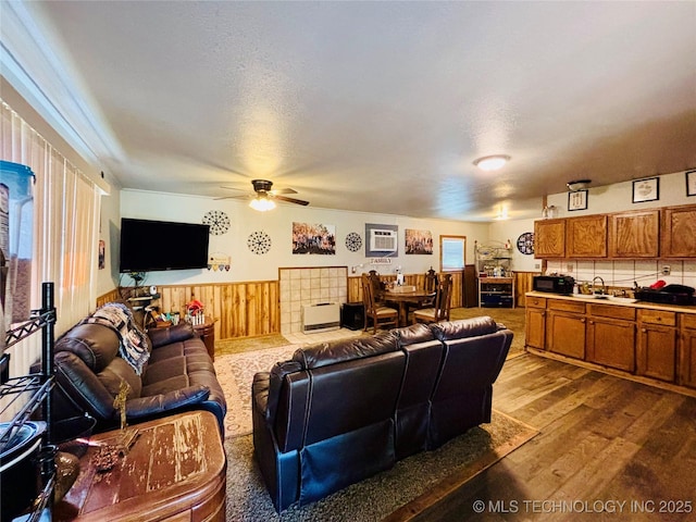 living area with a wall mounted air conditioner, wood finished floors, wainscoting, ceiling fan, and wood walls