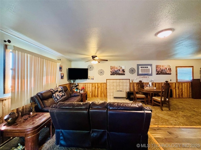 living room with a wall mounted air conditioner, a ceiling fan, a wainscoted wall, and wooden walls